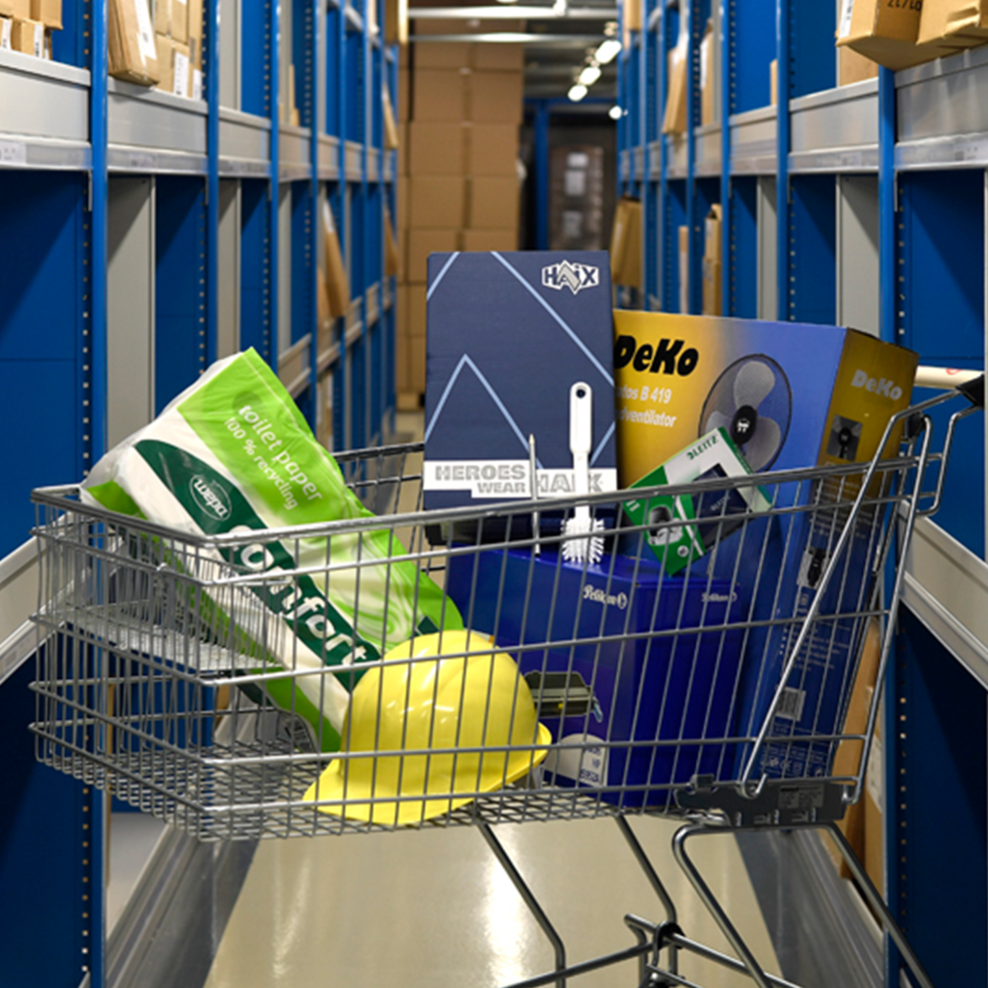 Einkaufswagen in Regalreihe mit Klopapier, Sicherheitshelm, Arbeitsschuhe, Toner, Ventilator